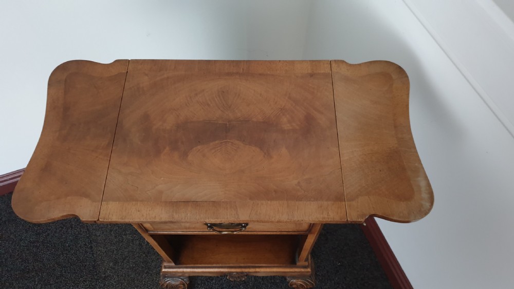 A Queen Anne style walnut bedside cabinet featuring side drop flaps, a single drawer over an open compartment, a carved shell apron, and cabriole legs. View III