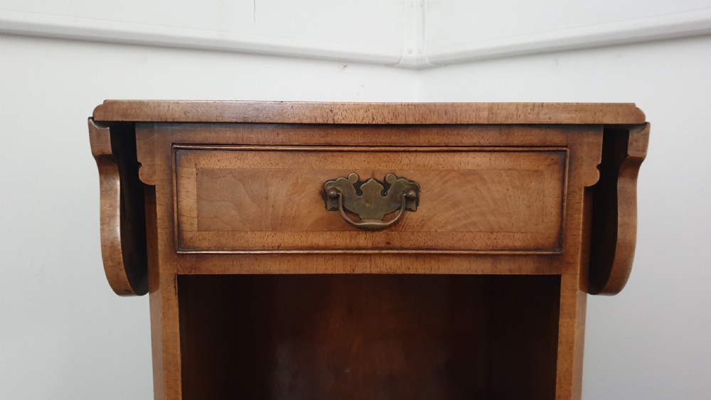 A Queen Anne style walnut bedside cabinet featuring side drop flaps, a single drawer over an open compartment, a carved shell apron, and cabriole legs. View VII