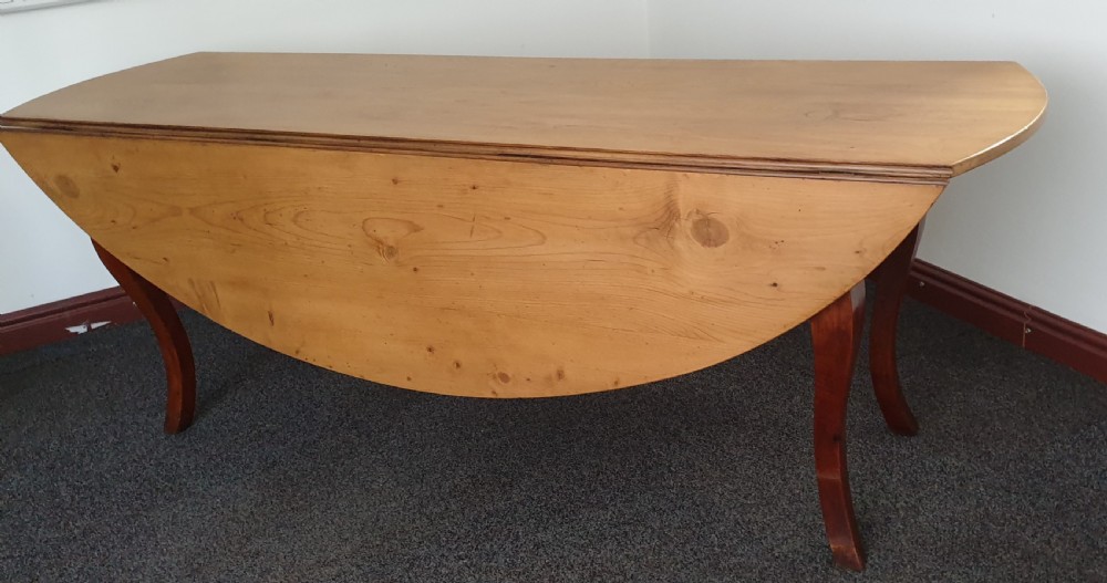 A large French farmhouse dining table featuring a light pine oval top supported by dark fruitwood cabriole legs. View IX