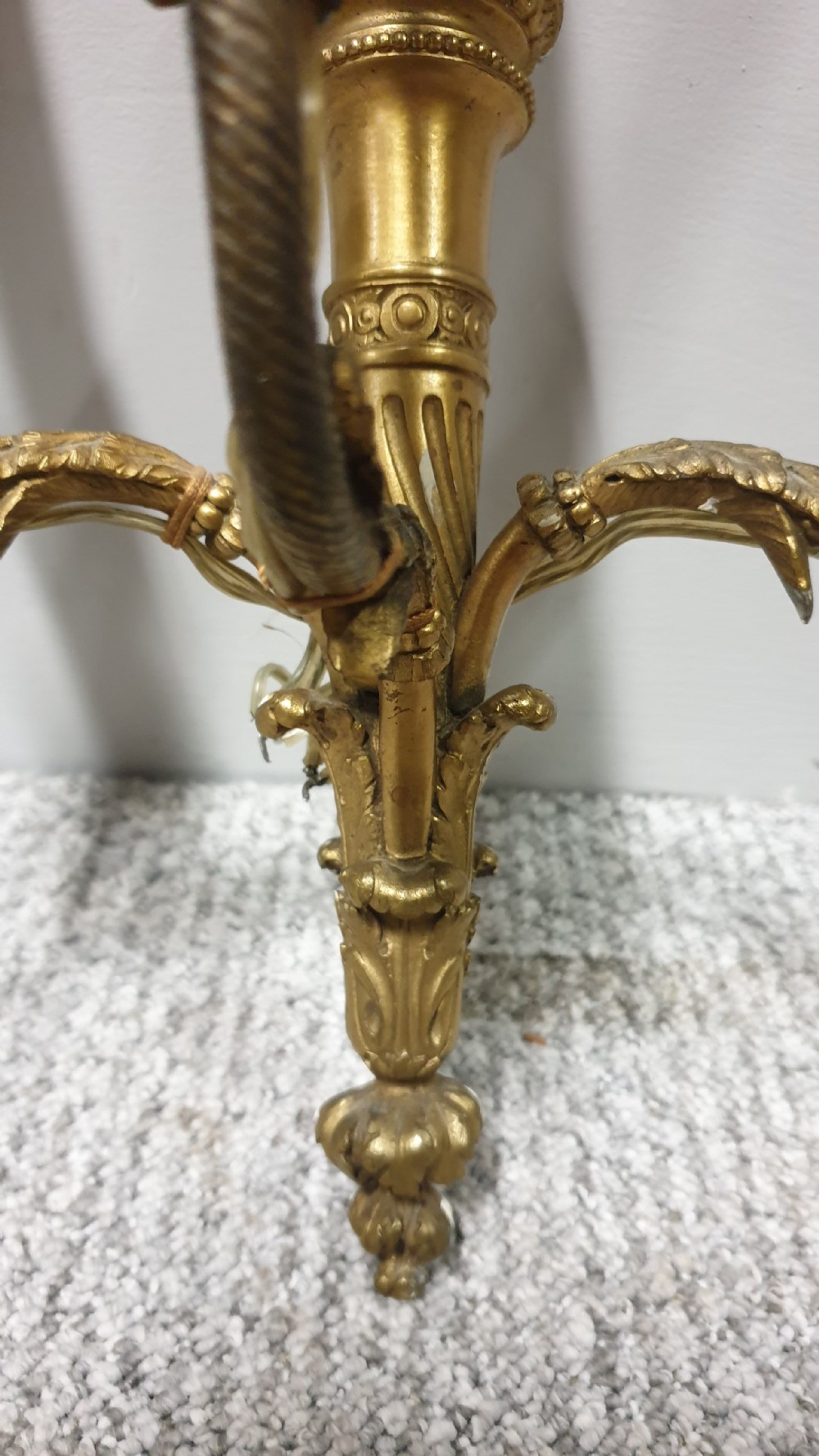 A pair of French Neoclassical gilt brass three-light wall sconces featuring fluted torch backplates, scrolling foliate arms, and cream candle sleeves. View VII