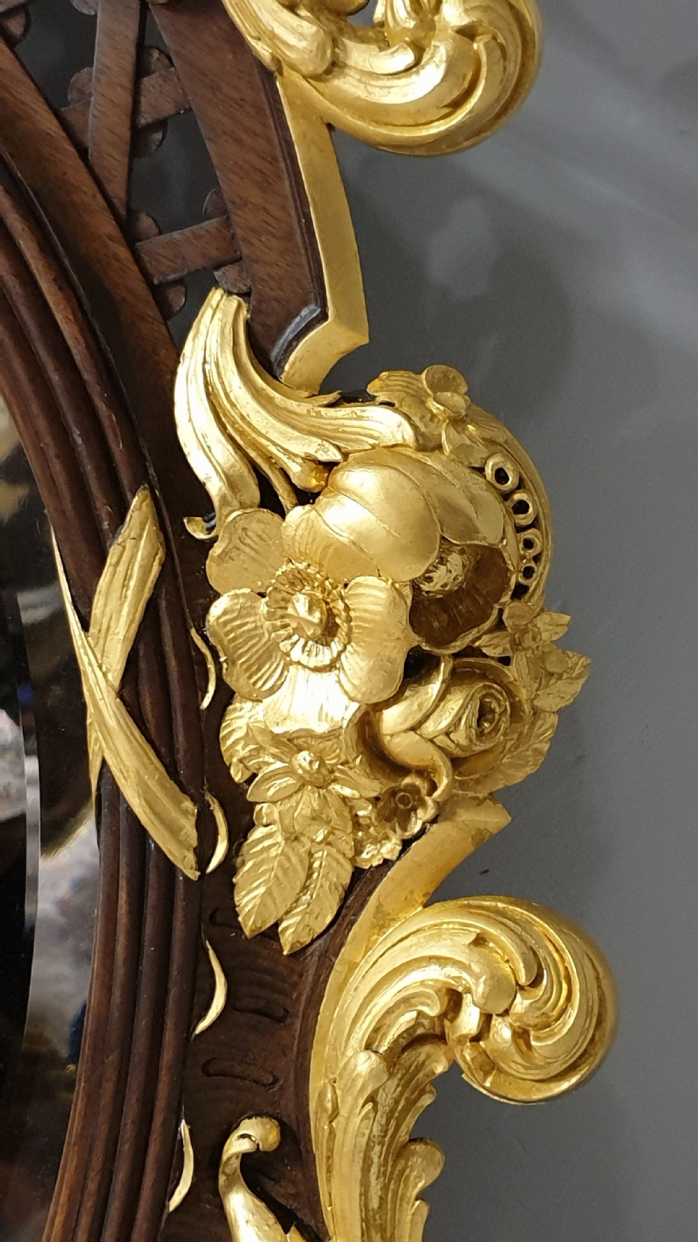 An ornate oval mahogany wall mirror featuring a carved eagle crest, parcel gilt acanthus leaf borders, side lattice panels, and a central classical mask motif at the base. View VII