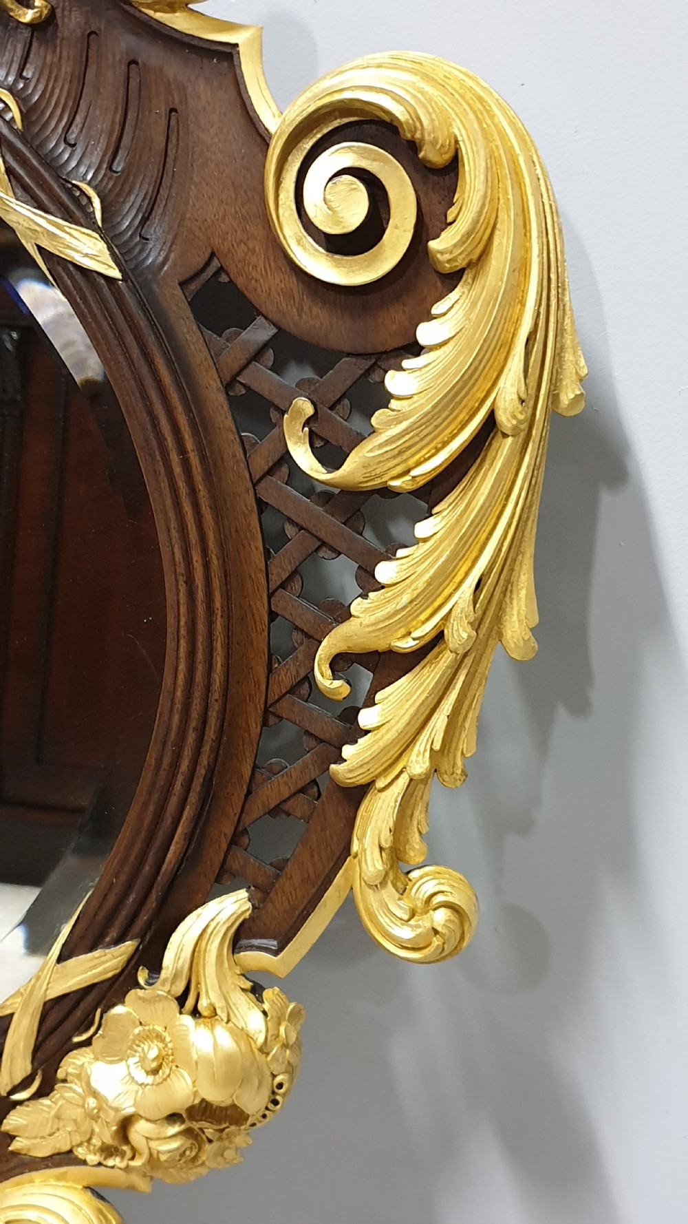 An ornate oval mahogany wall mirror featuring a carved eagle crest, parcel gilt acanthus leaf borders, side lattice panels, and a central classical mask motif at the base. View VIII