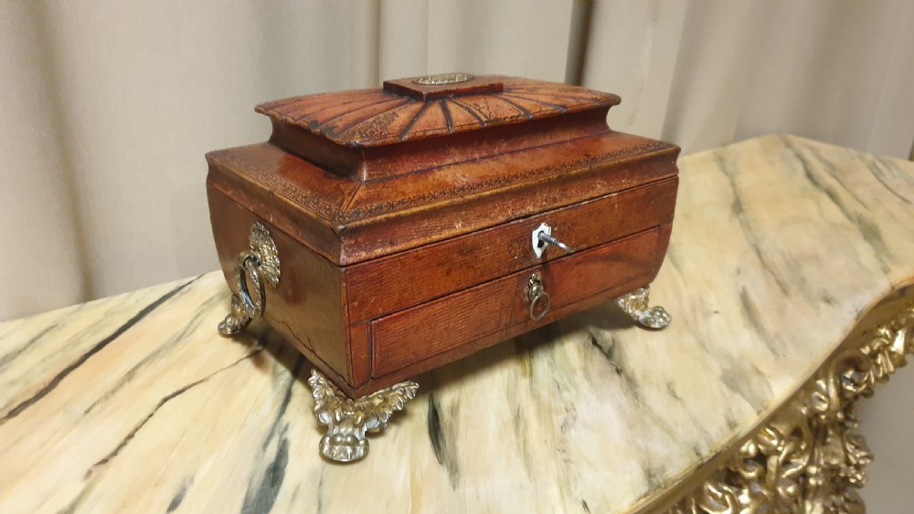 A Regency period tooled brown leather sewing box featuring a sarcophagus-shaped lid, cast brass claw feet, side ring handles, and a lower drawer. View VI