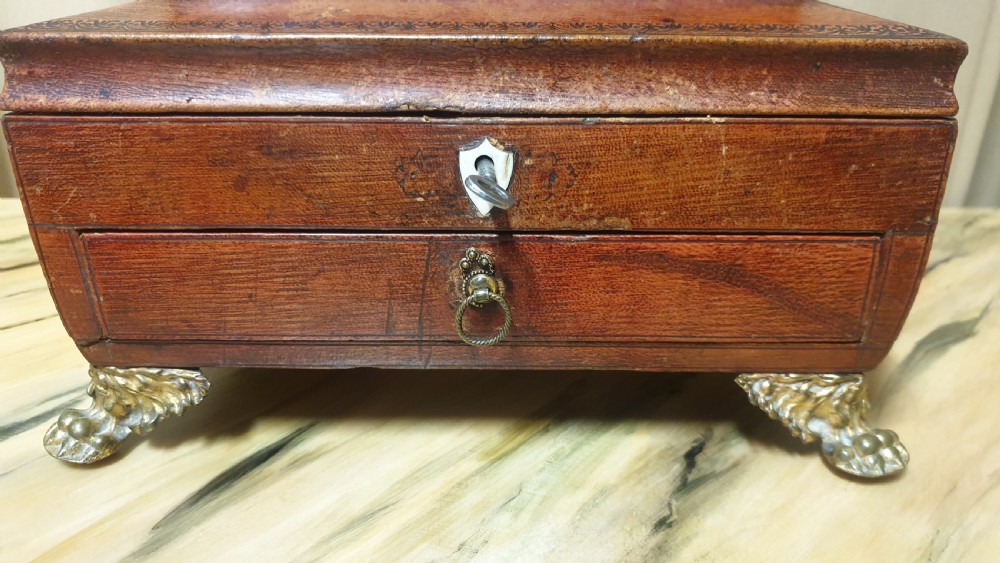 A Regency period tooled brown leather sewing box featuring a sarcophagus-shaped lid, cast brass claw feet, side ring handles, and a lower drawer. View VII