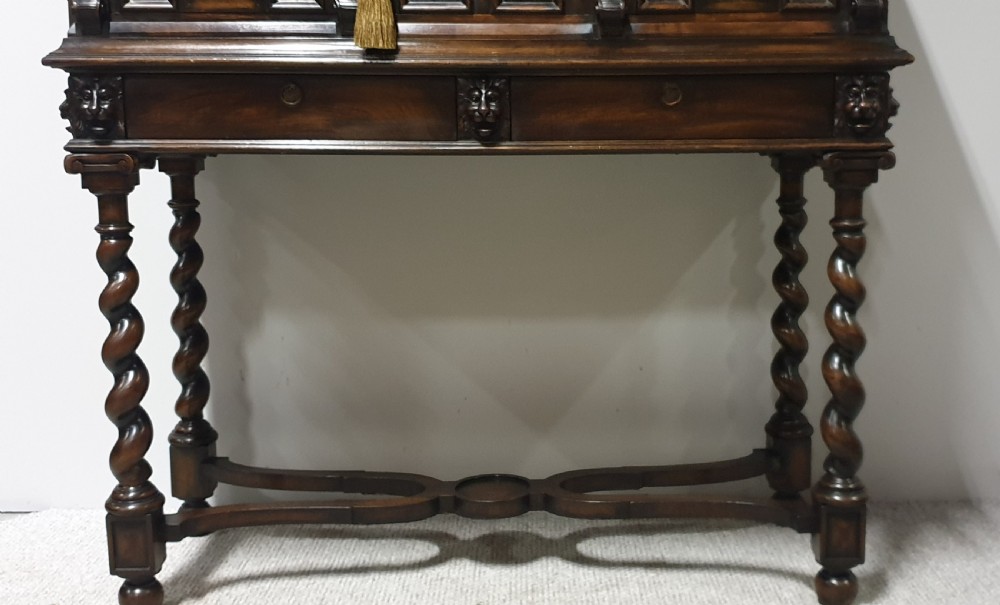 A dark carved walnut cabinet on a stand featuring mother of pearl inlay, carved lion mask details, geometric door panels, and barley twist legs with a stretcher. View II