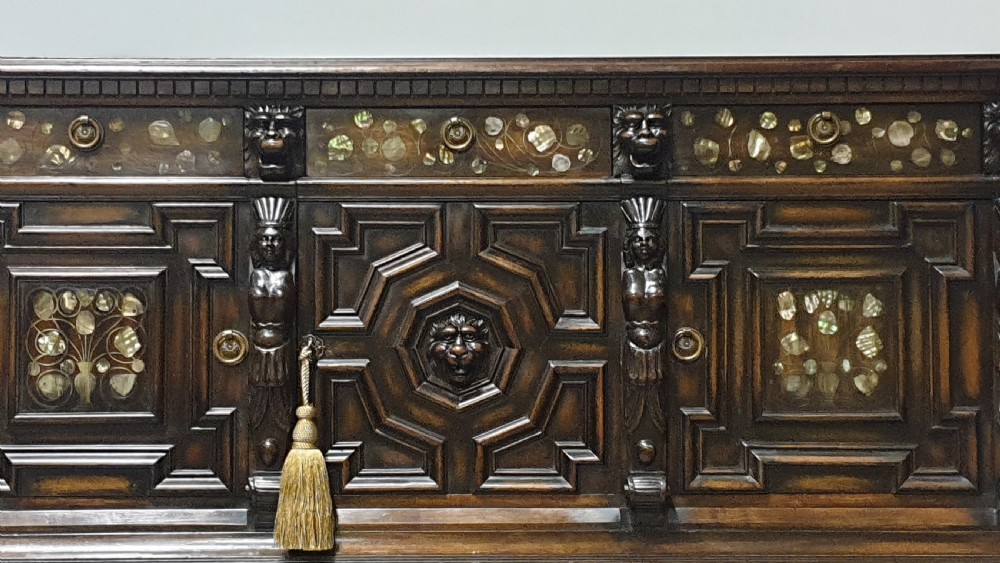 A dark carved walnut cabinet on a stand featuring mother of pearl inlay, carved lion mask details, geometric door panels, and barley twist legs with a stretcher. View IV