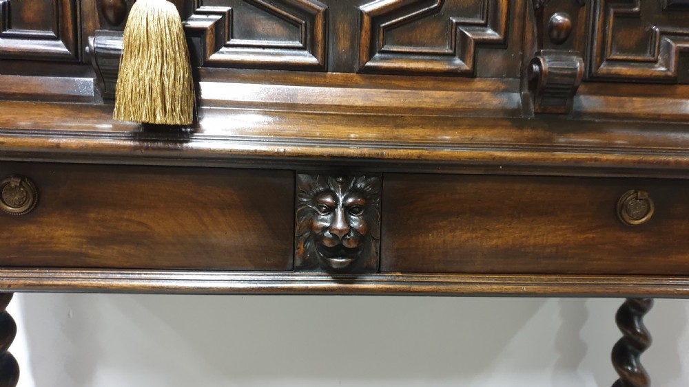 A dark carved walnut cabinet on a stand featuring mother of pearl inlay, carved lion mask details, geometric door panels, and barley twist legs with a stretcher. View X