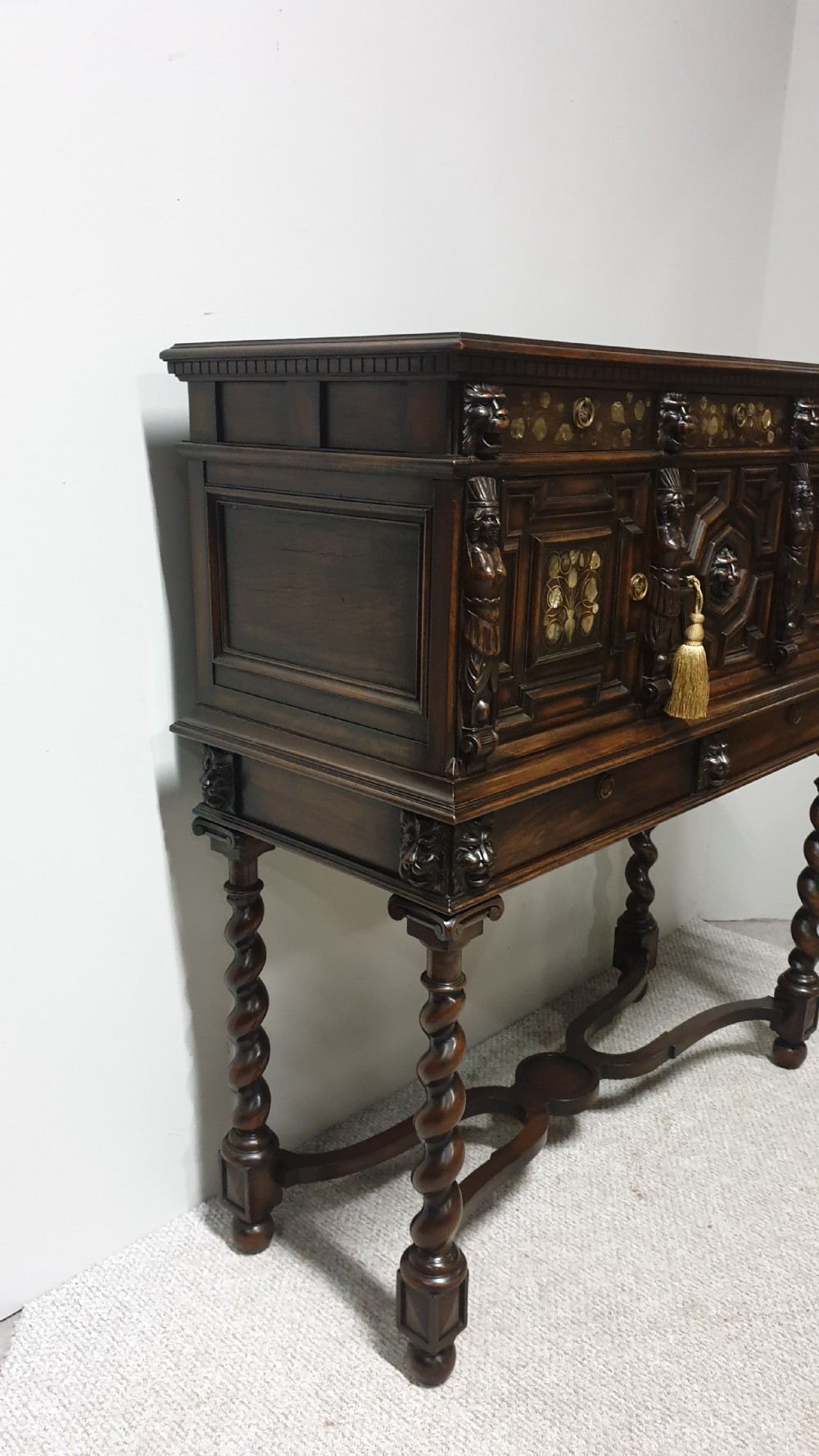 A dark carved walnut cabinet on a stand featuring mother of pearl inlay, carved lion mask details, geometric door panels, and barley twist legs with a stretcher. View XV