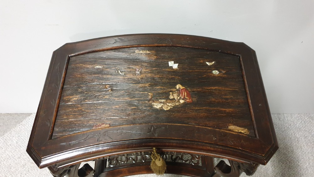 A dark brown Japanese lacquered work table featuring carved dragon head knees, a pierced apron, and a lower openwork shelf. View III