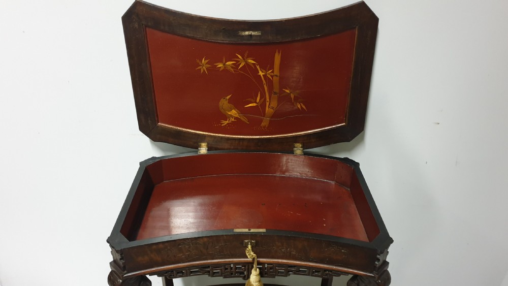 A dark brown Japanese lacquered work table featuring carved dragon head knees, a pierced apron, and a lower openwork shelf. View V