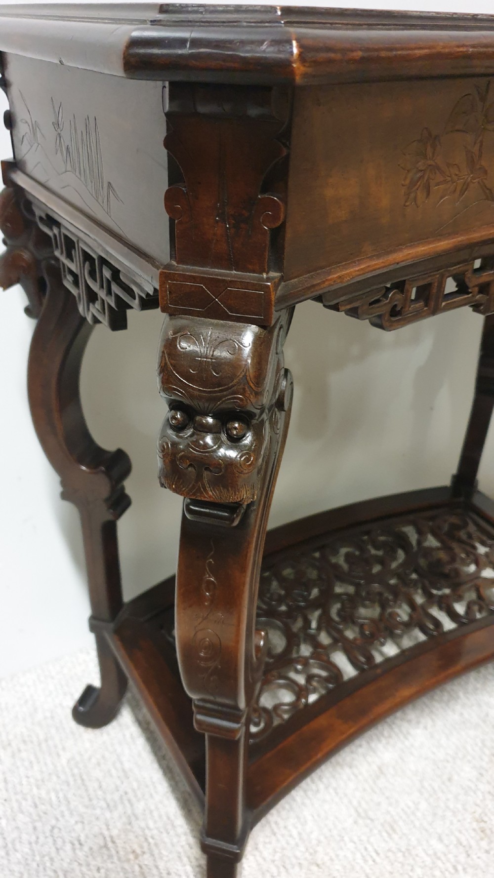 A dark brown Japanese lacquered work table featuring carved dragon head knees, a pierced apron, and a lower openwork shelf. View VIII