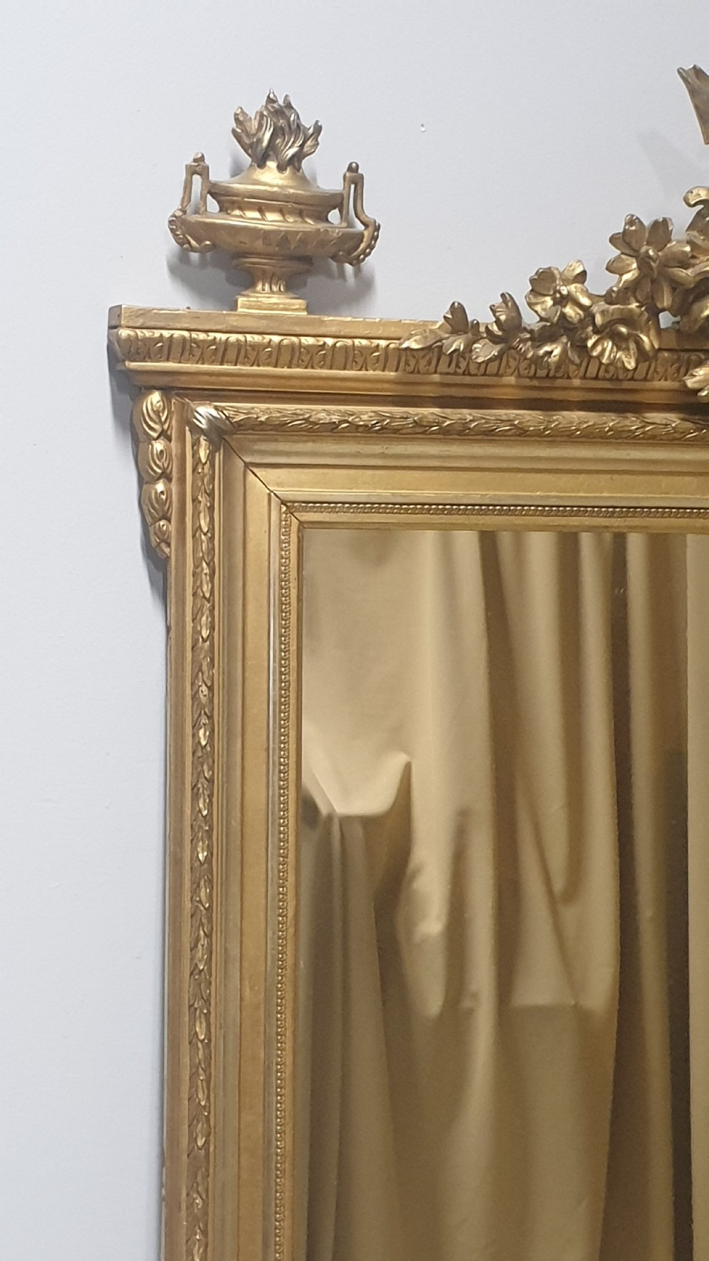 A tall rectangular French giltwood mirror featuring an ornate eagle crest flanked by urn finials and moulded frame detailing. View II