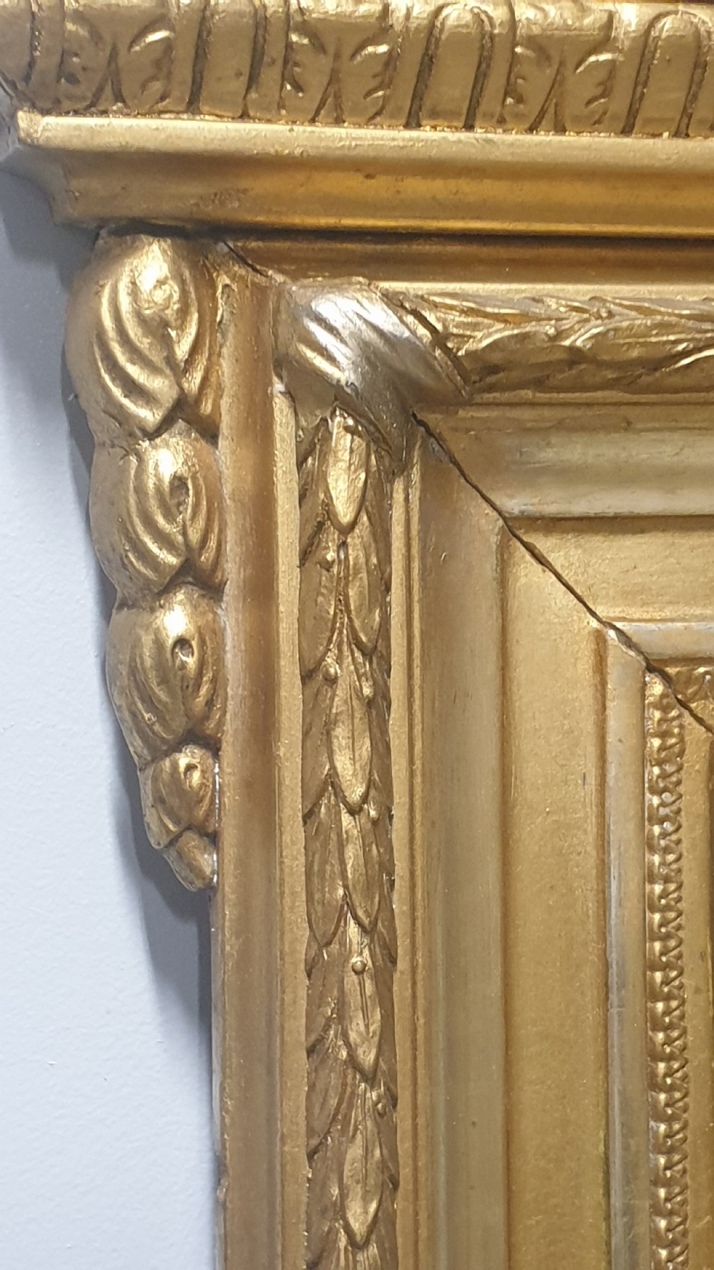 A tall rectangular French giltwood mirror featuring an ornate eagle crest flanked by urn finials and moulded frame detailing. View IV