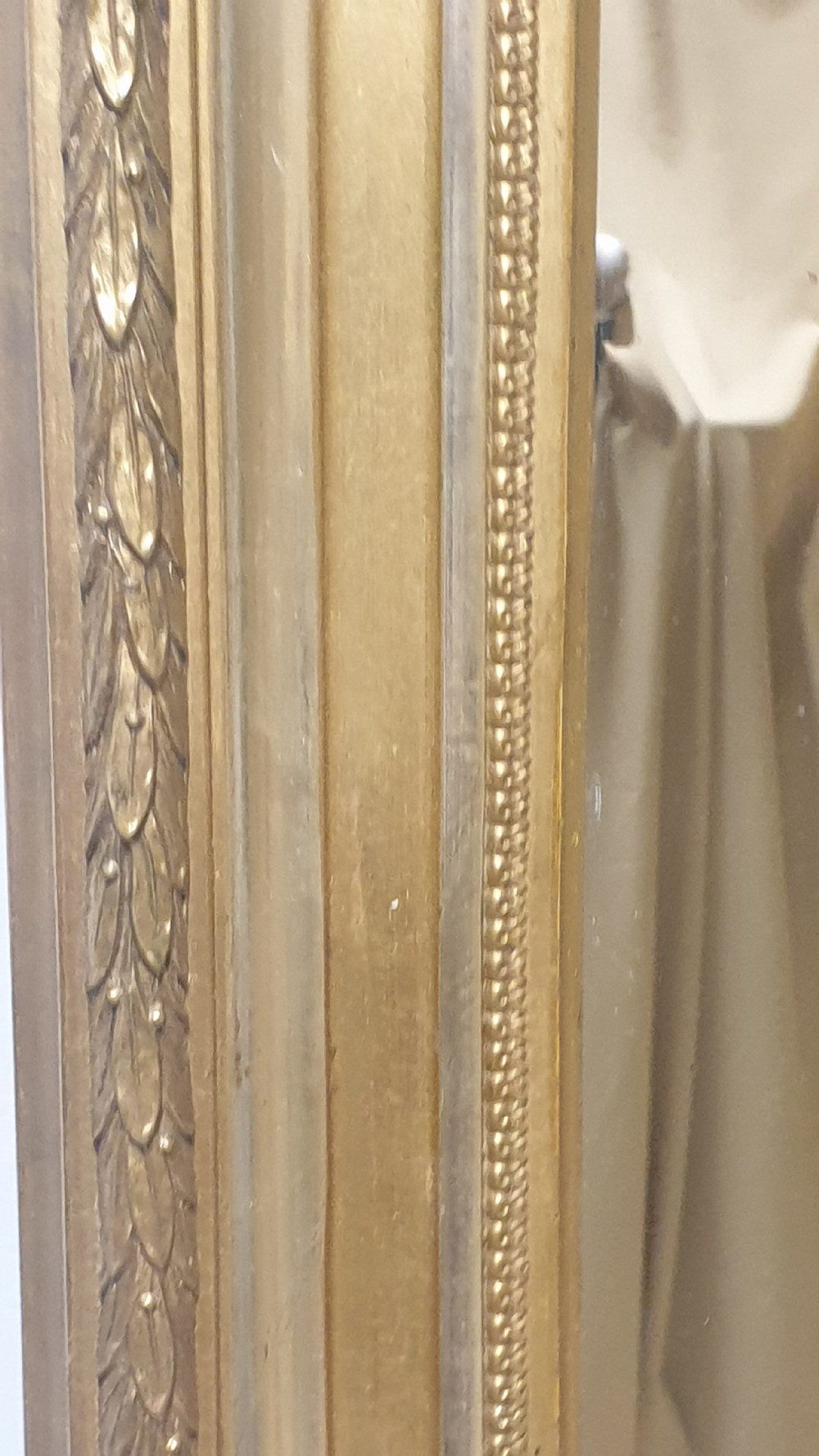 A tall rectangular French giltwood mirror featuring an ornate eagle crest flanked by urn finials and moulded frame detailing. View V
