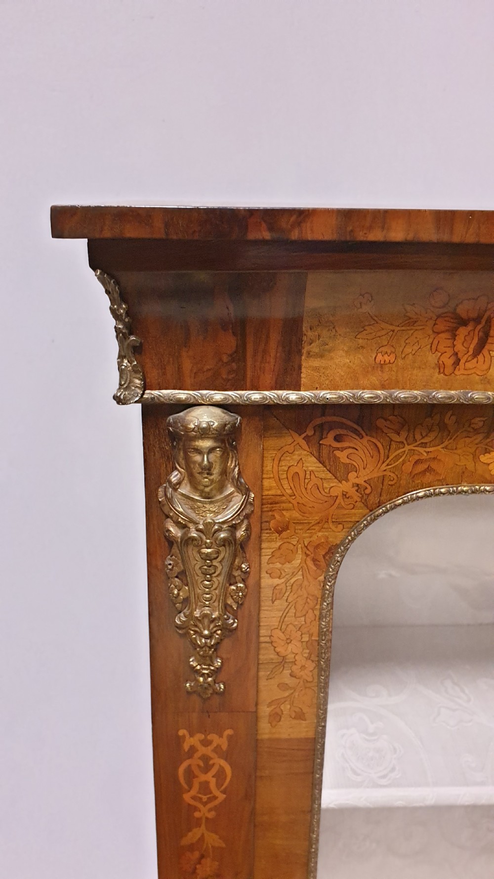 A Victorian walnut pier cabinet featuring floral marquetry inlays, gilt metal ormolu mounts, and a single glazed door opening to light-coloured shelves. View V