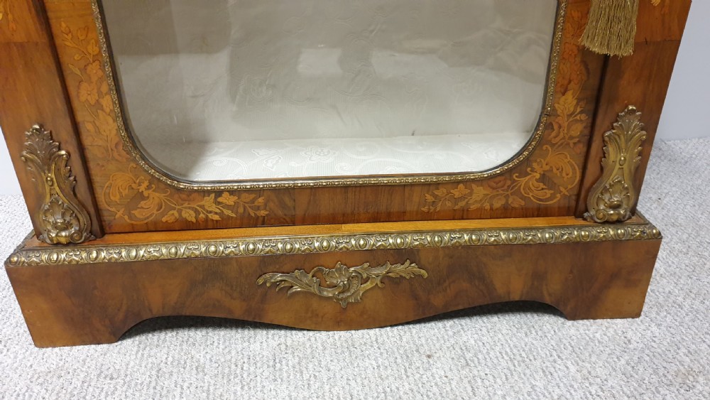 A Victorian walnut pier cabinet featuring floral marquetry inlays, gilt metal ormolu mounts, and a single glazed door opening to light-coloured shelves. View VII
