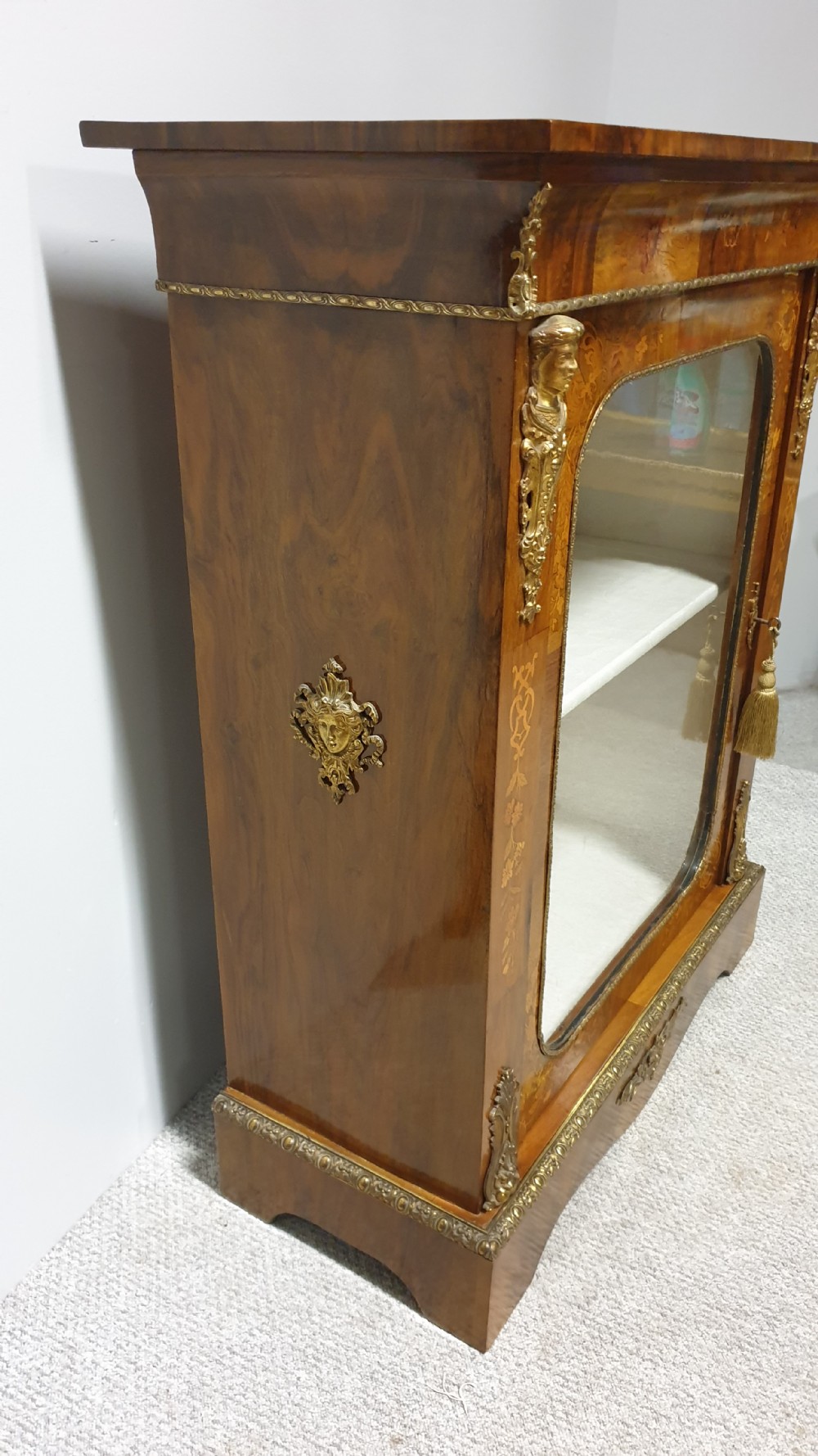 A Victorian walnut pier cabinet featuring floral marquetry inlays, gilt metal ormolu mounts, and a single glazed door opening to light-coloured shelves. View XI