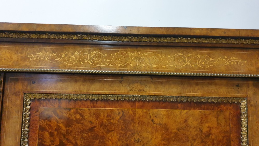 A Victorian burr walnut credenza featuring a central inlaid cupboard door flanked by two curved glazed display side cabinets and decorative gilt ormolu mounts. View II
