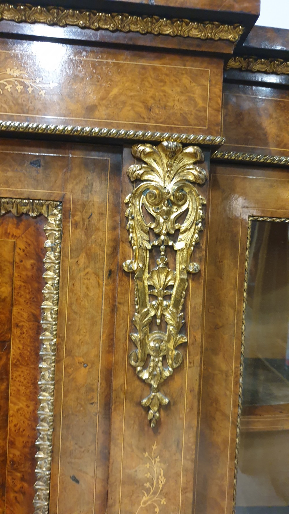A Victorian burr walnut credenza featuring a central inlaid cupboard door flanked by two curved glazed display side cabinets and decorative gilt ormolu mounts. View V