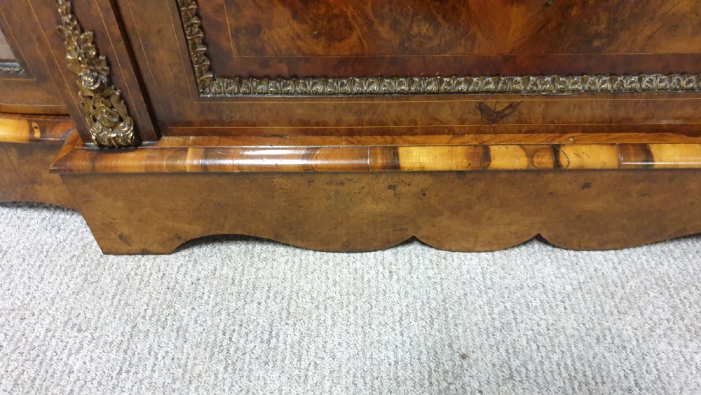 A Victorian burr walnut credenza featuring a central inlaid cupboard door flanked by two curved glazed display side cabinets and decorative gilt ormolu mounts. View VI