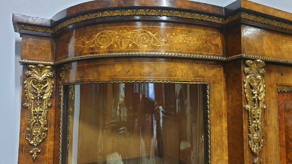 A Victorian burr walnut credenza featuring a central inlaid cupboard door flanked by two curved glazed display side cabinets and decorative gilt ormolu mounts. View VII