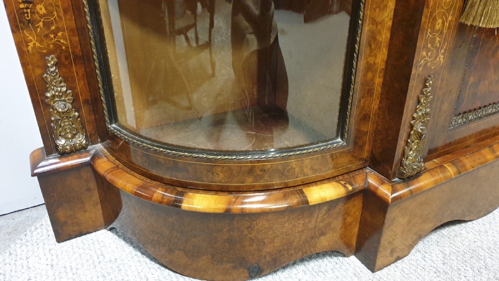 A Victorian burr walnut credenza featuring a central inlaid cupboard door flanked by two curved glazed display side cabinets and decorative gilt ormolu mounts. View VIII