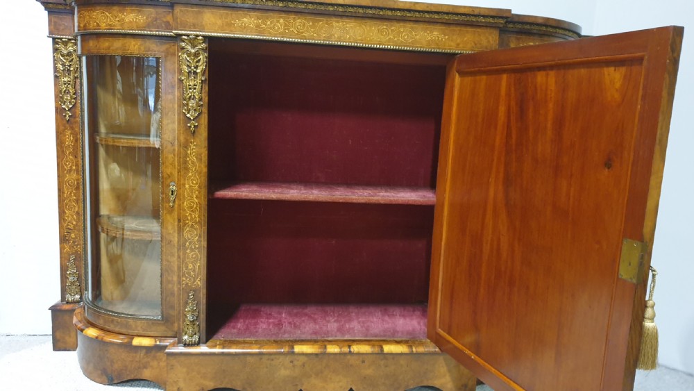 A Victorian burr walnut credenza featuring a central inlaid cupboard door flanked by two curved glazed display side cabinets and decorative gilt ormolu mounts. View X