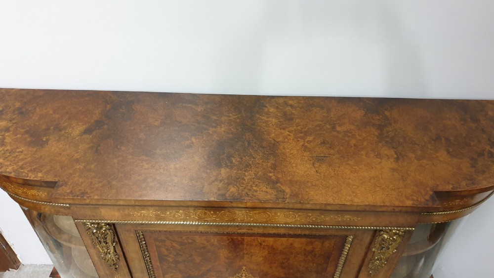 A Victorian burr walnut credenza featuring a central inlaid cupboard door flanked by two curved glazed display side cabinets and decorative gilt ormolu mounts. View XI