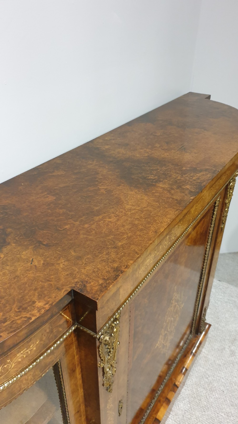 A Victorian burr walnut credenza featuring a central inlaid cupboard door flanked by two curved glazed display side cabinets and decorative gilt ormolu mounts. View XIII