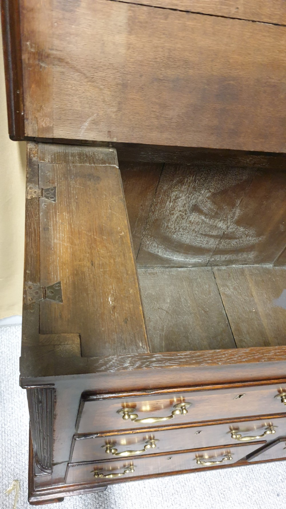 A dark oak Georgian Lancashire coffer featuring nine fielded panel drawer fronts with brass swan-neck handles and a hinged top lid resting on ogee bracket feet. View X