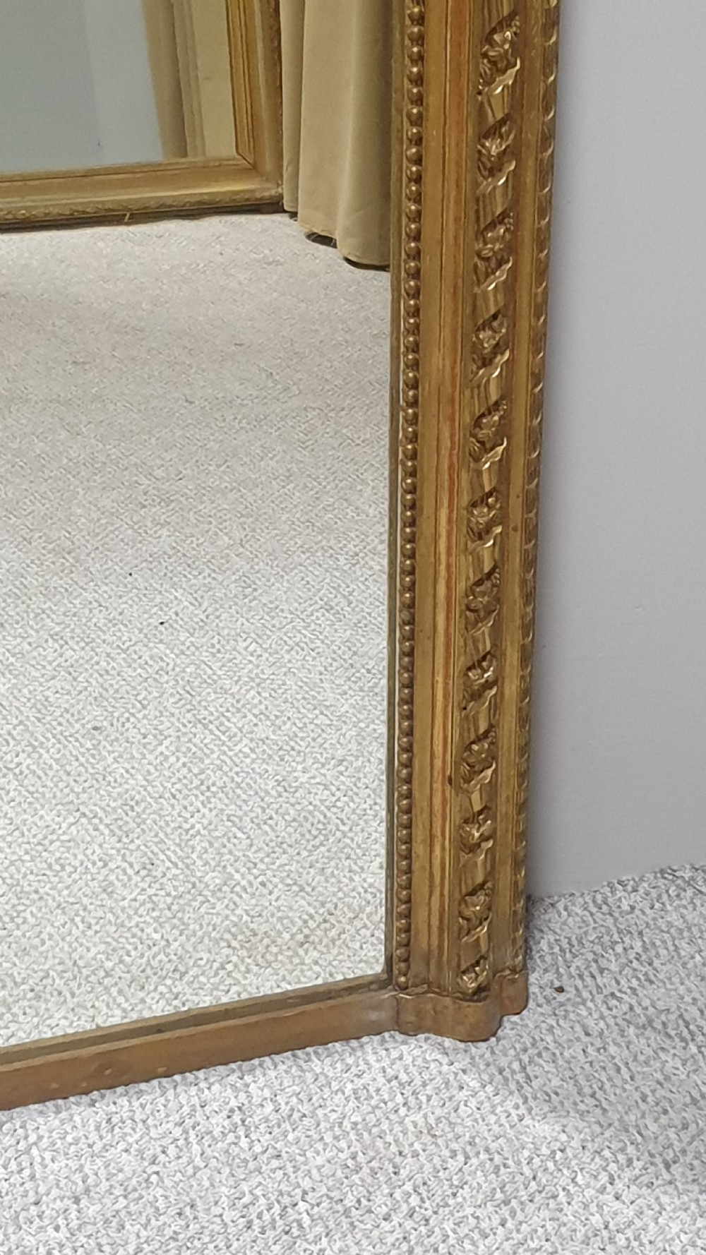 A tall rectangular French giltwood pier mirror topped with an ornate carved crest featuring a musical lyre and foliage. View III
