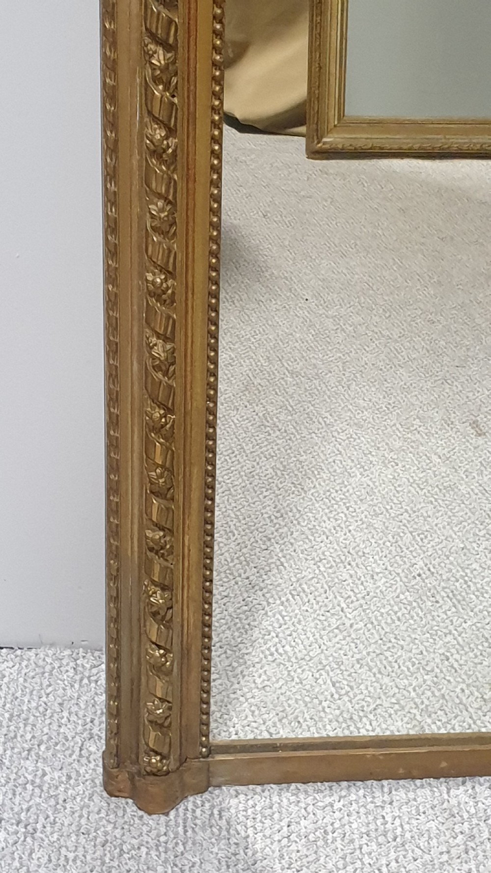 A tall rectangular French giltwood pier mirror topped with an ornate carved crest featuring a musical lyre and foliage. View V