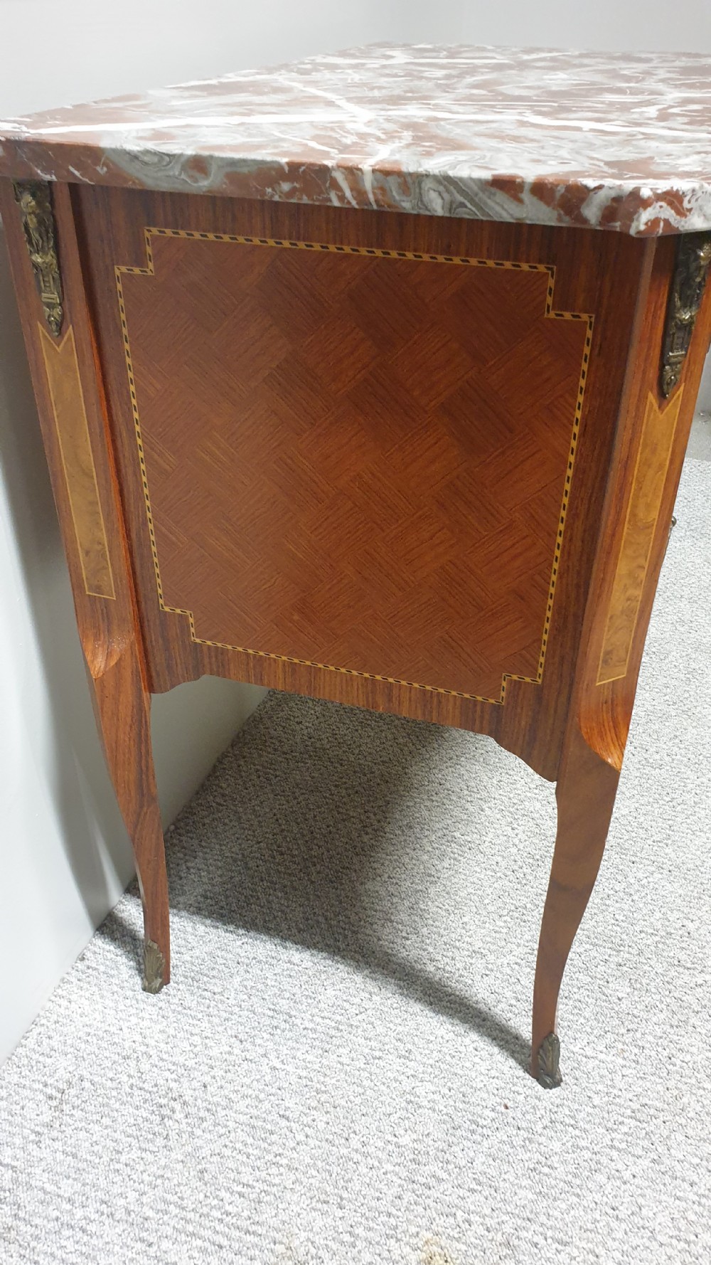 A French-style wooden commode with two drawers, featuring a white and red veined marble top, central floral marquetry medallion, bronze handles, and cabriole legs. View VII