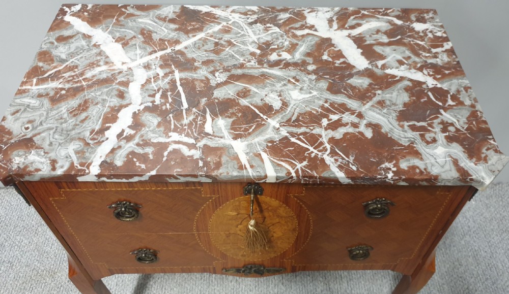A French-style wooden commode with two drawers, featuring a white and red veined marble top, central floral marquetry medallion, bronze handles, and cabriole legs. View VIII