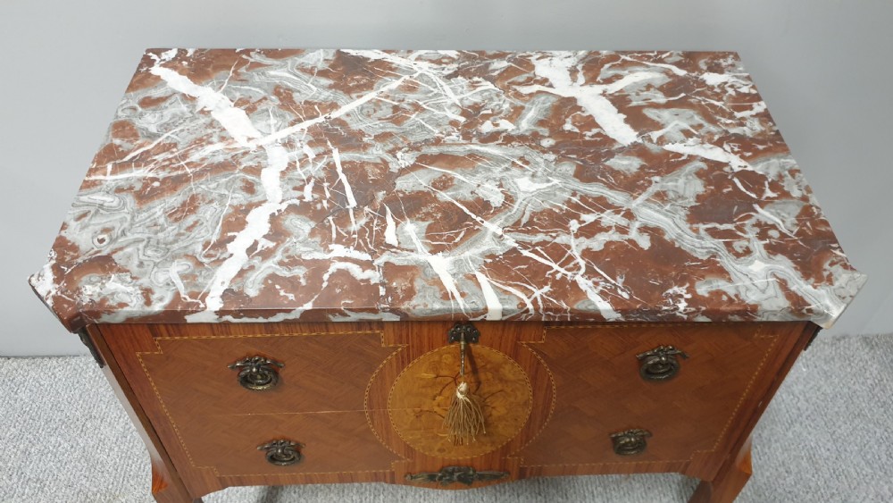 A French-style wooden commode with two drawers, featuring a white and red veined marble top, central floral marquetry medallion, bronze handles, and cabriole legs. View IX