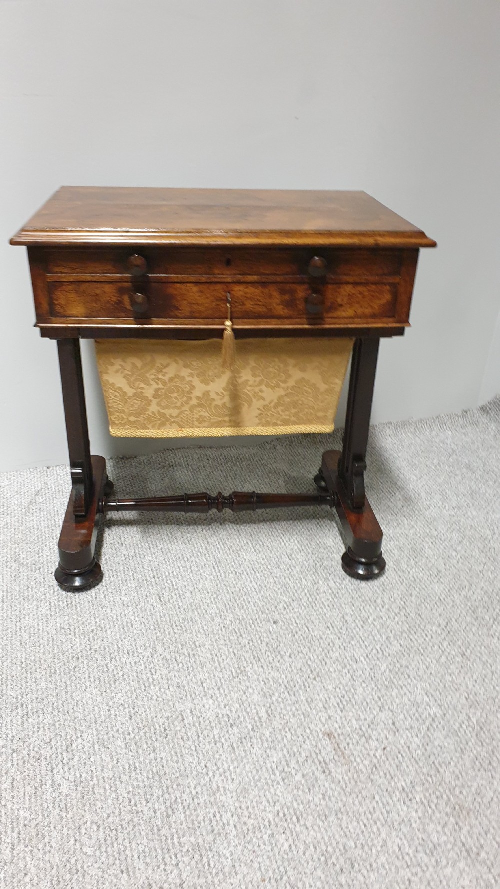 A William IV mahogany sewing table featuring two drawers with turned knobs, a gold fabric well underneath, and trestle supports joined by a turned stretcher. View II