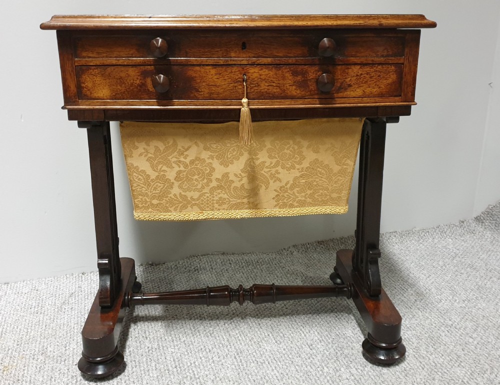 A William IV mahogany sewing table featuring two drawers with turned knobs, a gold fabric well underneath, and trestle supports joined by a turned stretcher. View III