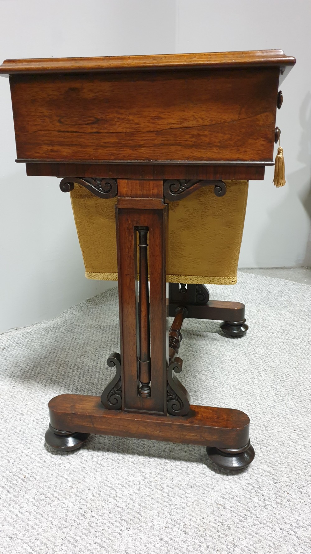 A William IV mahogany sewing table featuring two drawers with turned knobs, a gold fabric well underneath, and trestle supports joined by a turned stretcher. View V