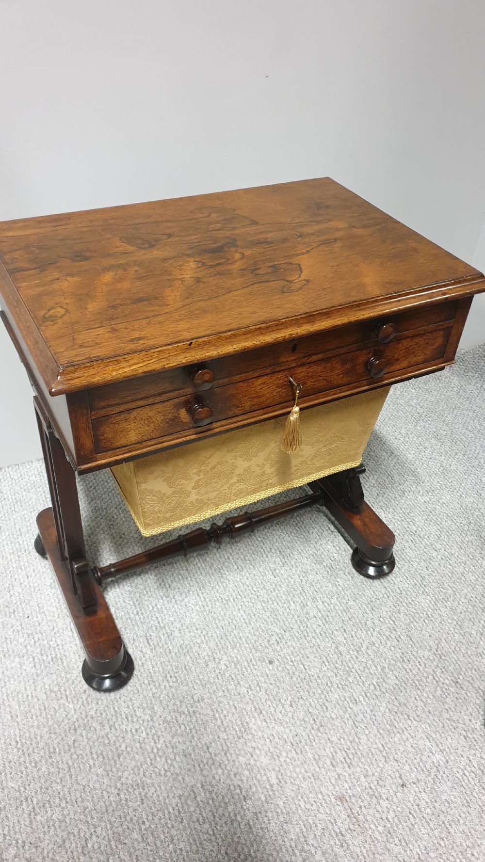 A William IV mahogany sewing table featuring two drawers with turned knobs, a gold fabric well underneath, and trestle supports joined by a turned stretcher. View XII