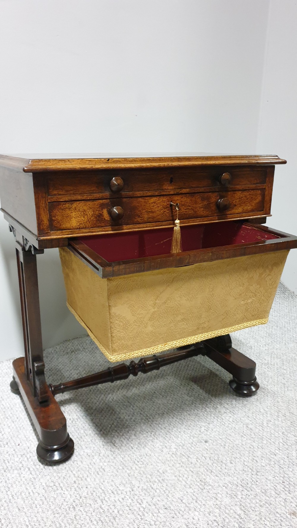 A William IV mahogany sewing table featuring two drawers with turned knobs, a gold fabric well underneath, and trestle supports joined by a turned stretcher. View XIV