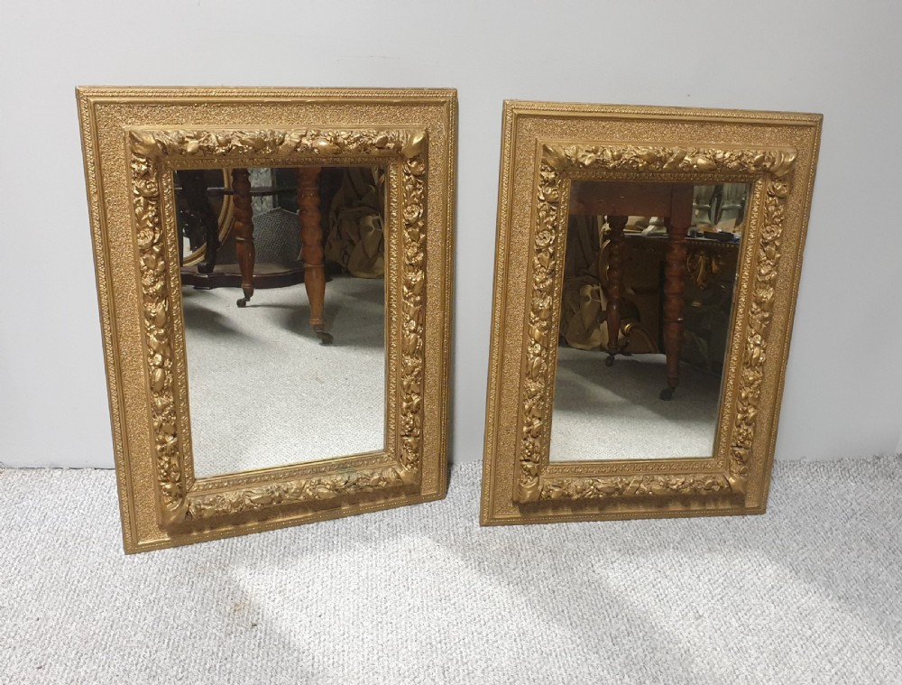 A matching pair of rectangular Victorian wall mirrors featuring ornate floral gesso moulding and a burnished gold finish. View II