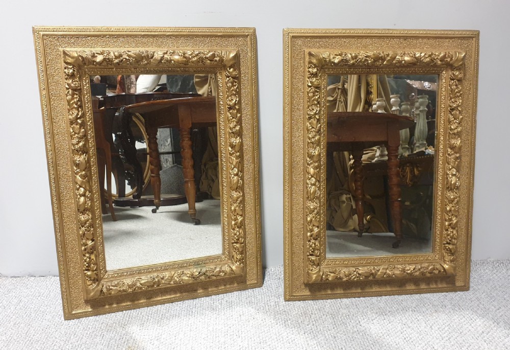 A matching pair of rectangular Victorian wall mirrors featuring ornate floral gesso moulding and a burnished gold finish. View V