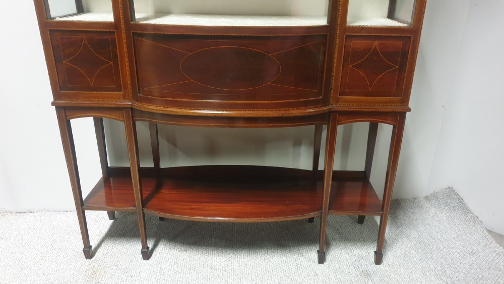 An Edwardian inlaid mahogany display cabinet featuring glazed doors, string marquetry details, and slender tapered legs connected by a lower shelf. View III
