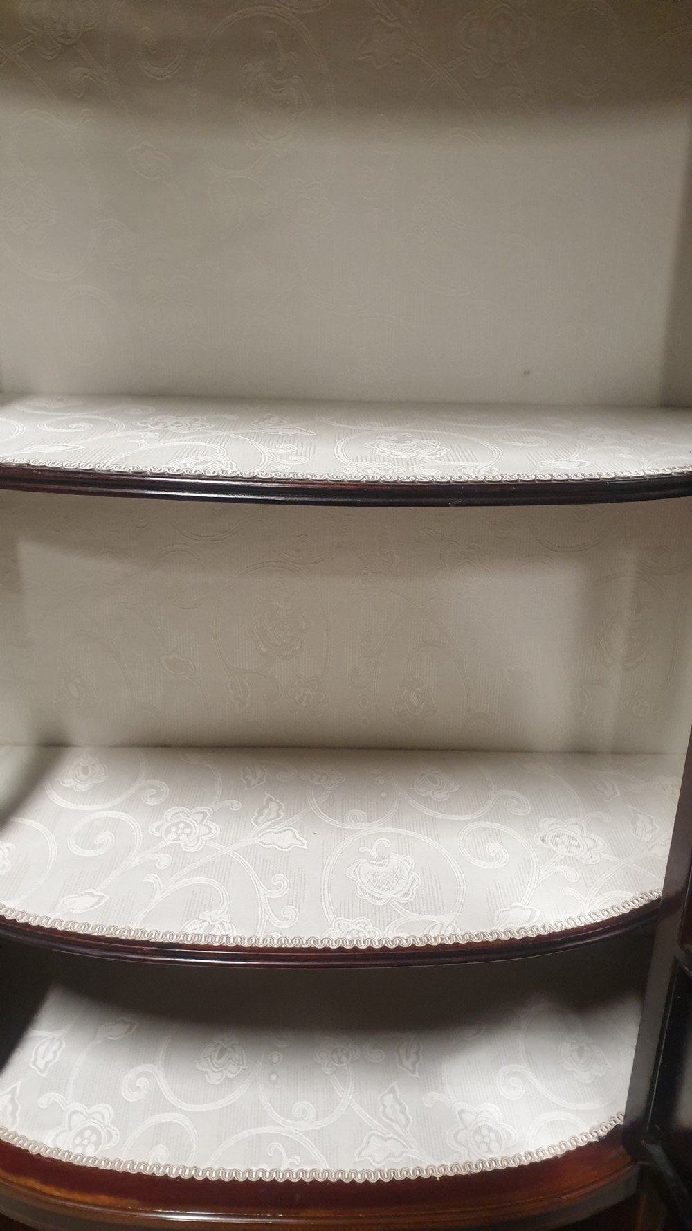 An Edwardian inlaid mahogany display cabinet featuring glazed doors, string marquetry details, and slender tapered legs connected by a lower shelf. View IX
