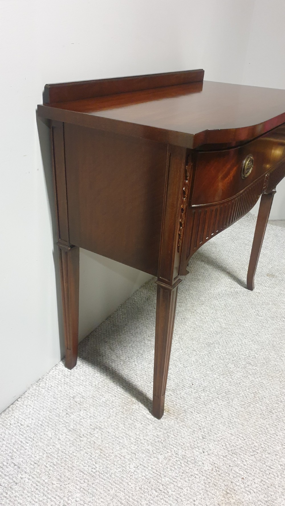 A small mahogany sideboard featuring a single curved drawer, brass ring handles, and fluted tapered legs. View II
