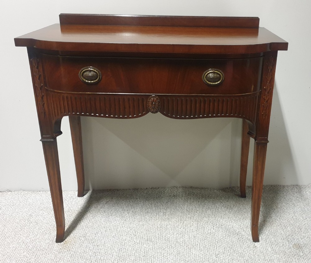 A small mahogany sideboard featuring a single curved drawer, brass ring handles, and fluted tapered legs. View III