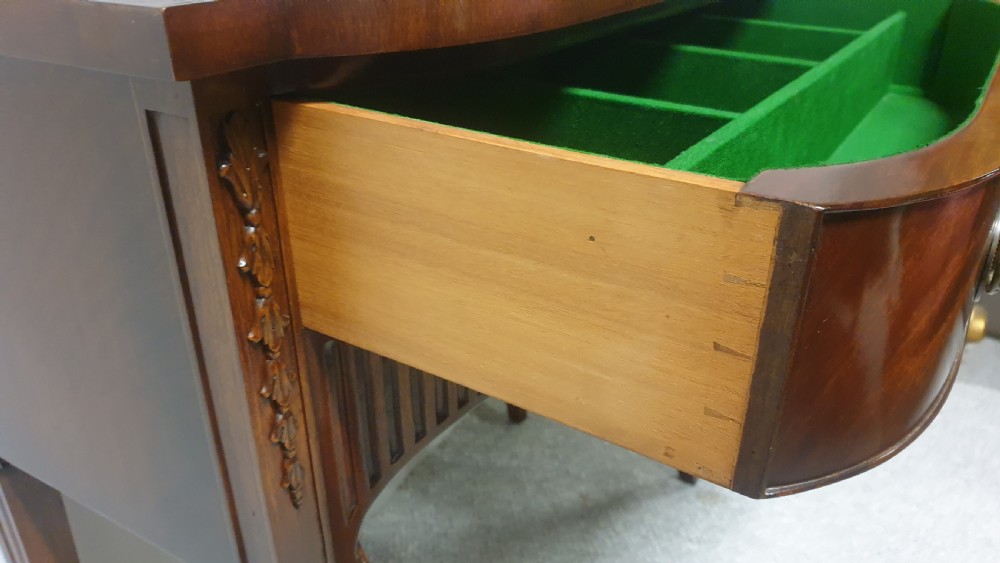A small mahogany sideboard featuring a single curved drawer, brass ring handles, and fluted tapered legs. View VII