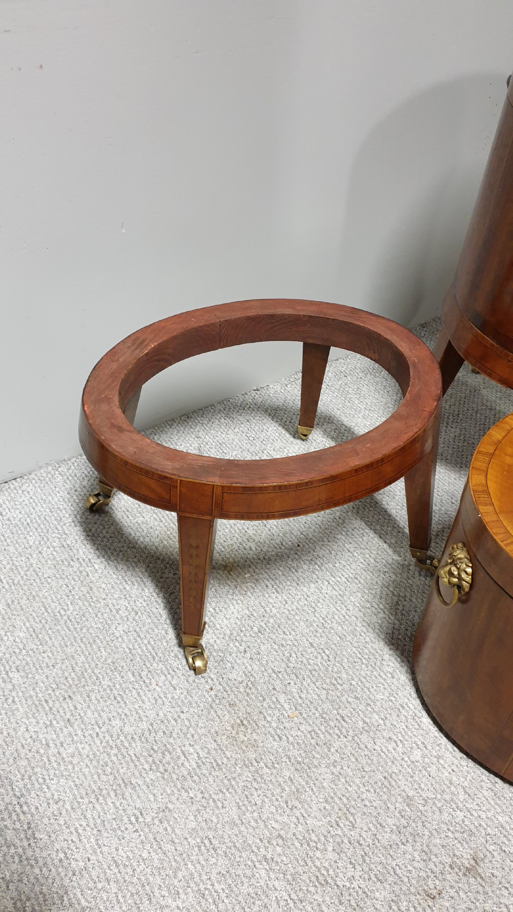 A pair of cylindrical satinwood wine coolers featuring inlaid marquetry oval medallions, lion mask brass side handles, key tassels, tapered legs, and brass castors. View XVII