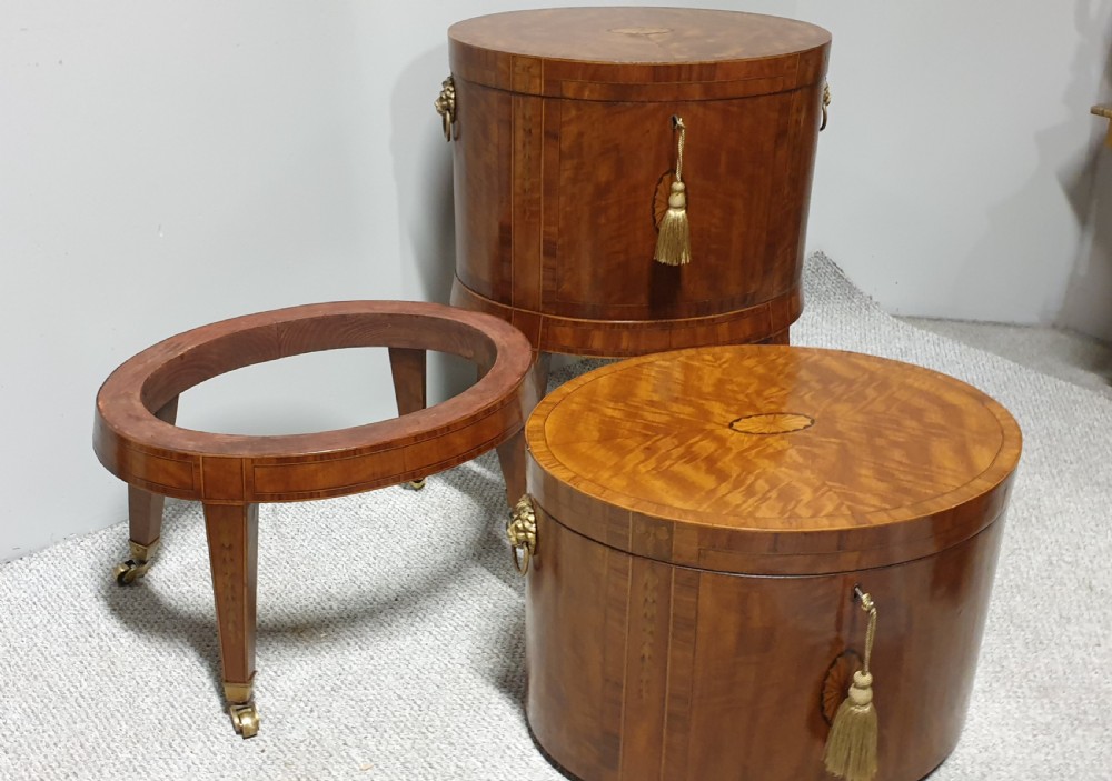 A pair of cylindrical satinwood wine coolers featuring inlaid marquetry oval medallions, lion mask brass side handles, key tassels, tapered legs, and brass castors. View XVIII