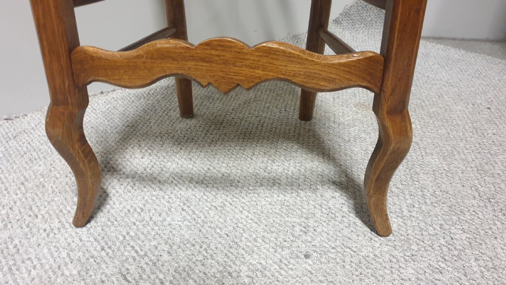 A set of four French Provincial oak dining chairs featuring carved floral top rails, wavy ladderbacks, woven rush seats, and cabriole front legs. View XI
